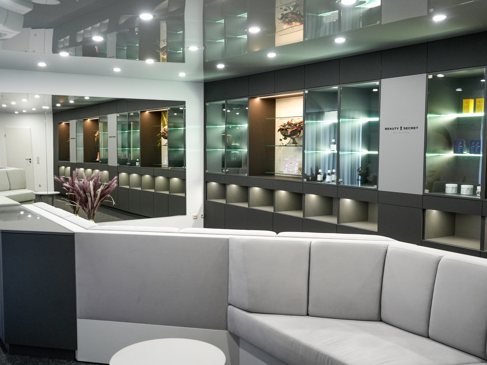 Lounge und beleuchtete Produktvitrinen im Institut von Beauty Secret by Alina in Paderborn